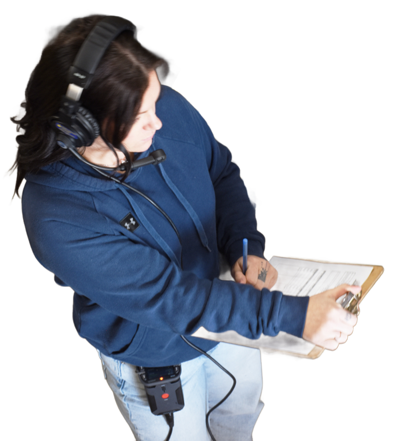 Person wearing a headset with mic, writing on a clipboard in a blue hoodie.